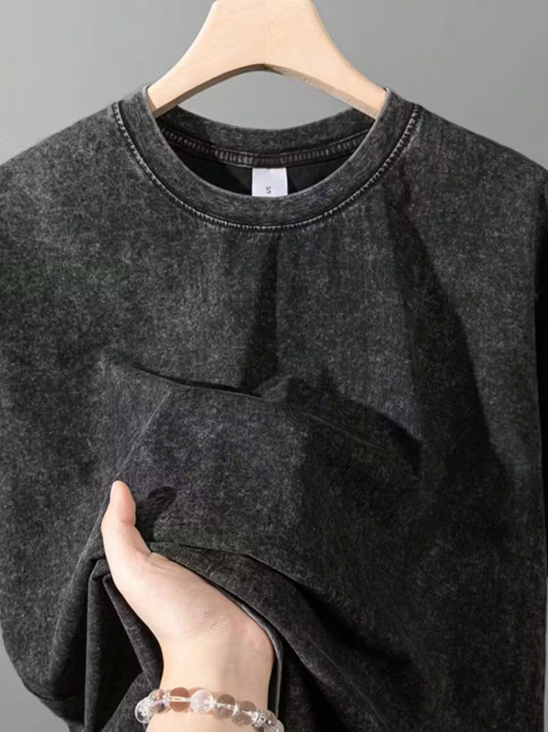 Dark gray sweatshirt on a hanger with a hand adjusting it, against a neutral background